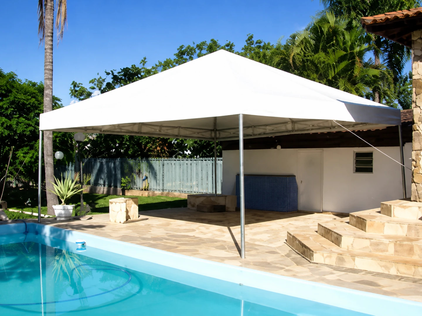 Tenda piramidal instalada em área de lazer com piscina